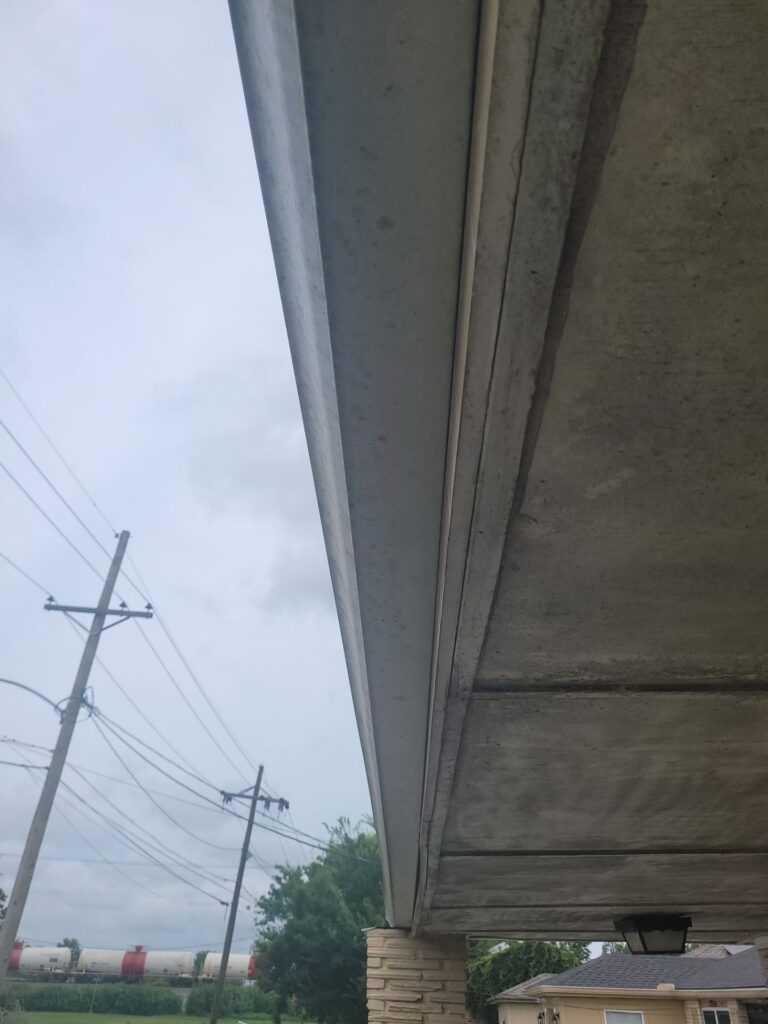 An upward-facing view of a residential soffit and metal fascia board under the eaves of a roof, showing the building's exterior overhang.