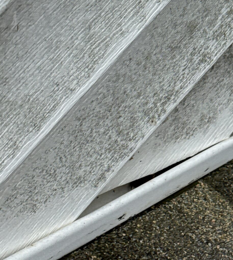 This photo shows a gap between the vinyl siding and the metal trim along the edge of the roof or gable, indicating improper installation or shifting.